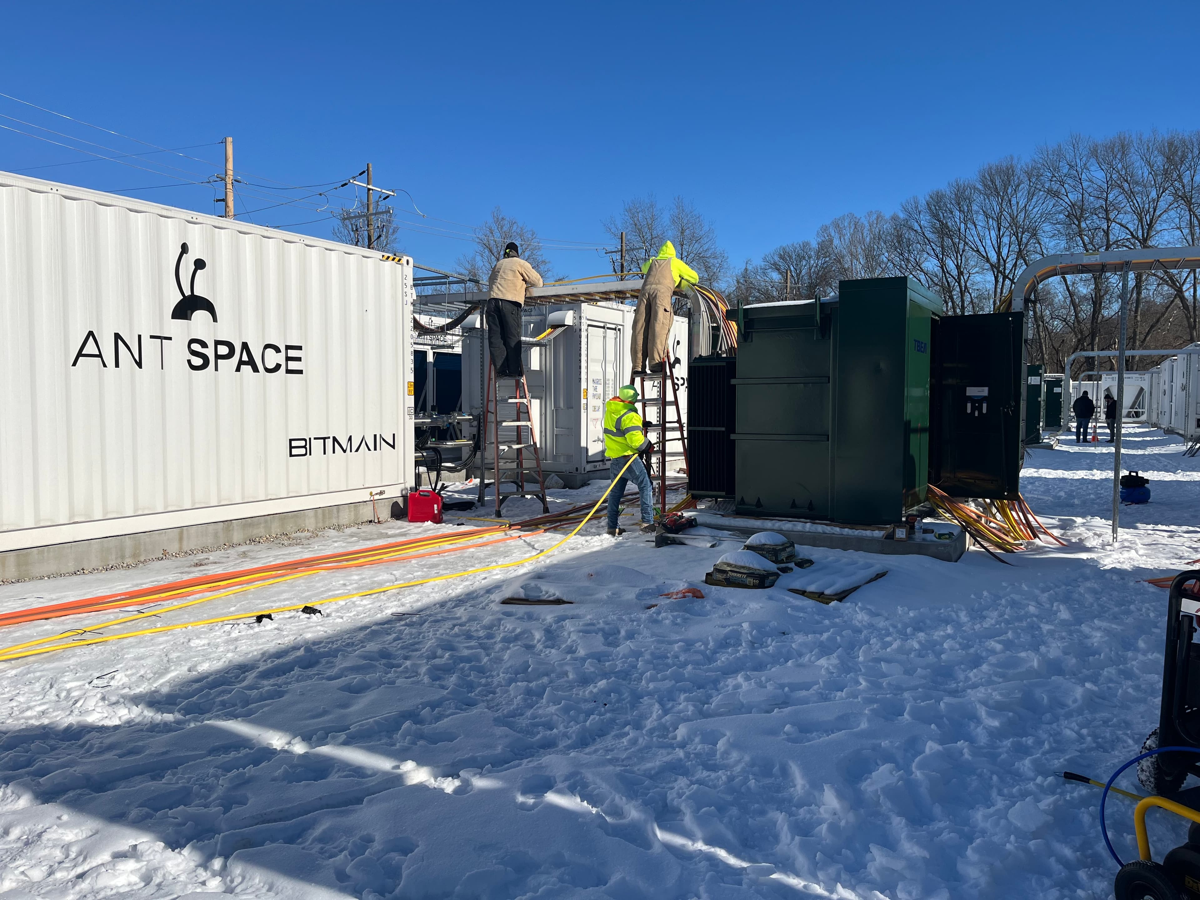 Technicians routing power cabling to BITMAIN ANTSPACE containers in snow