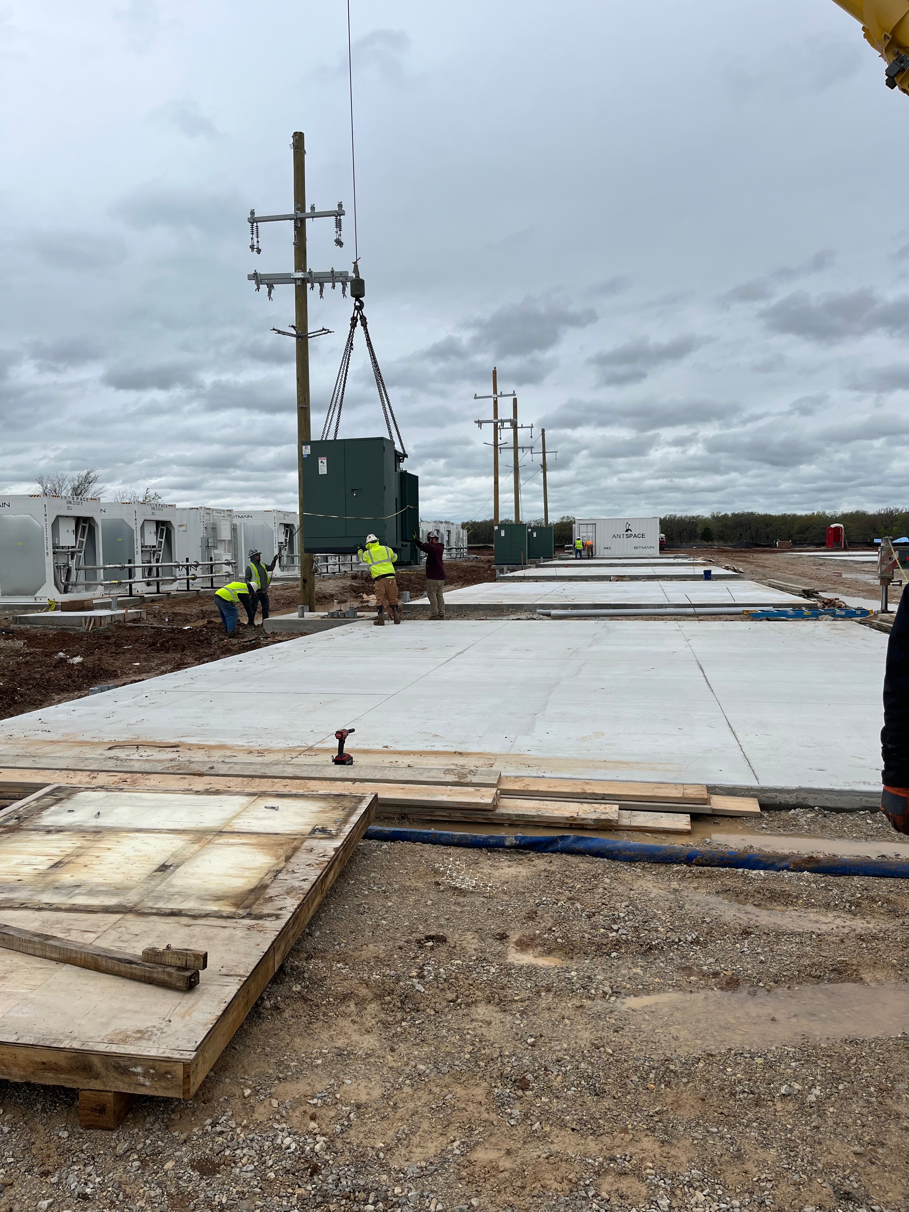 Crane lowering a power transformer onto a concrete pad near ANTSPACE units